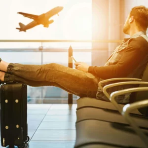 Airport guide for first-time international flyers waiting at departure gate with luggage