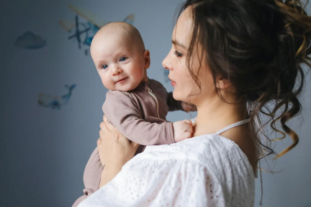 A mother lovingly holding her newborn baby in a nursery room, perfect for parents preparing for flying with a newborn.